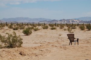 Plastic chair with creosote and distant mountains.